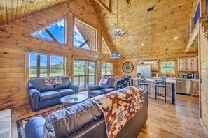 A spacious living room with a large sofa, a coffee table, and a dining area with a kitchen in the background.