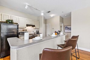 A modern kitchen with white cabinets, a black refrigerator, and a central island with bar stools.