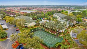 Vue aérienne d’un quartier résidentiel avec des maisons, un court de tennis et un parking.