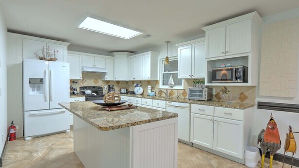 A modern kitchen with white cabinetry, a central island, and a microwave on the countertop.