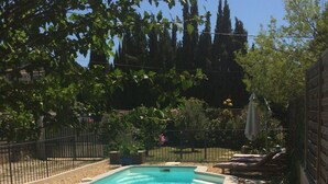 Una piscina rectangular con un borde de azulejos, rodeada por una valla metálica y grava.