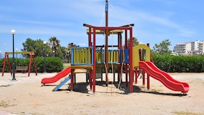 A playground with slides and climbing structures, benches, and a paved walkway. - Cozy studio 50m from the beach of Rafina & 700m from the port (Rafina)
