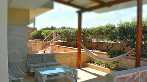 A covered outdoor seating area with a sofa, a glass-top table, and a hammock. - Cozy studio 50m from the beach of Rafina & 700m from the port (Rafina)