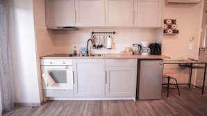A compact kitchen with white cabinets, a built-in oven, a refrigerator, and a coffee maker. - Cozy studio 50m from the beach of Rafina & 700m from the port (Rafina)