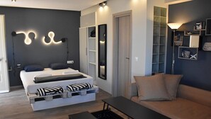 A modern bedroom with a bed, bedside tables, a sofa, and a built-in wardrobe. - Cozy studio 50m from the beach of Rafina & 700m from the port (Rafina)