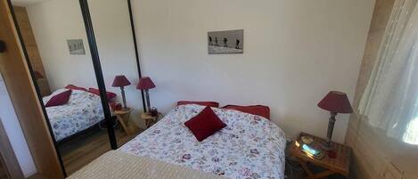 A bedroom with a large bed, two bedside tables with lamps, a mirror, and a wall-mounted picture.