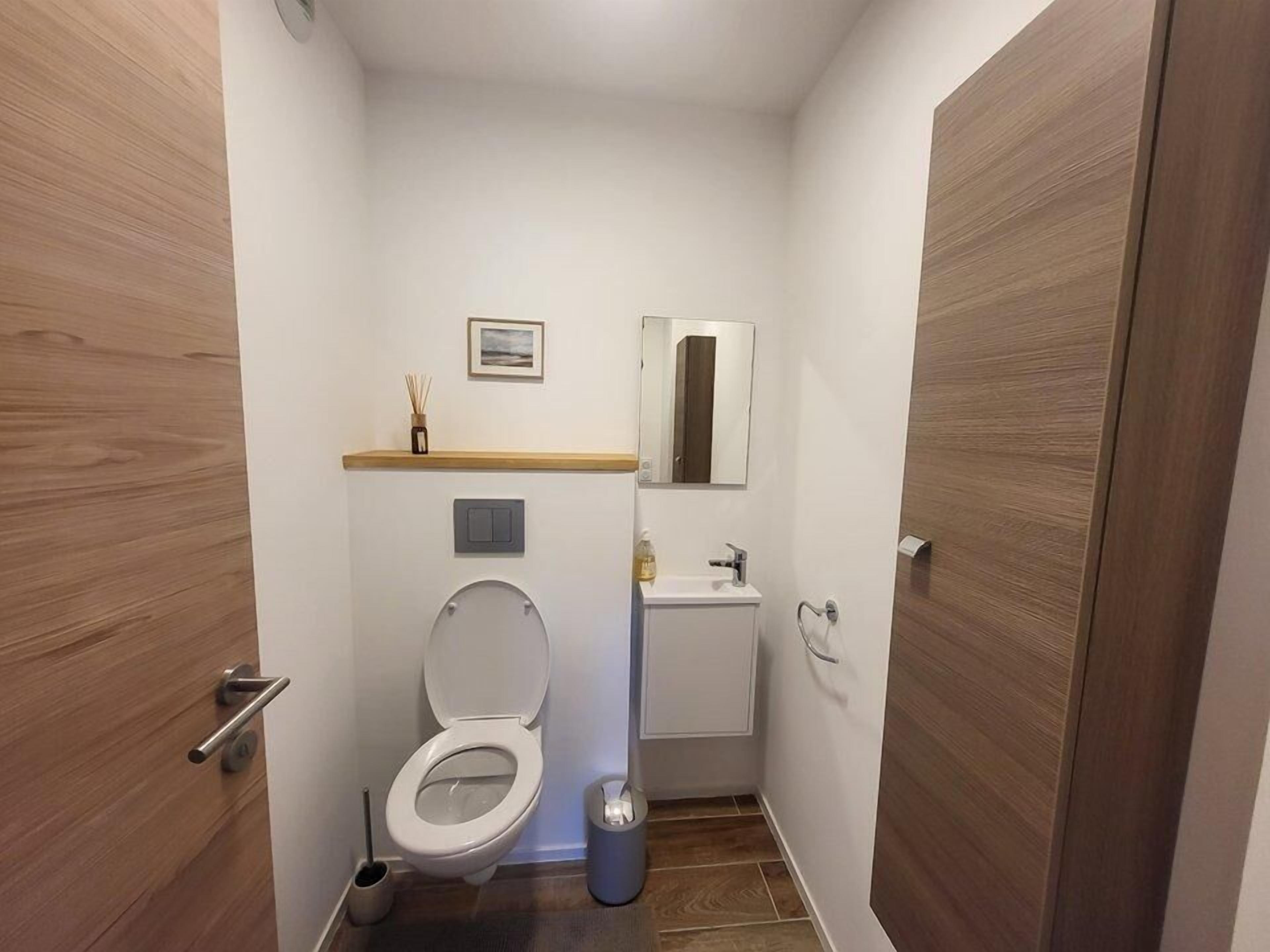 A compact bathroom with a toilet, sink, and mirror.
