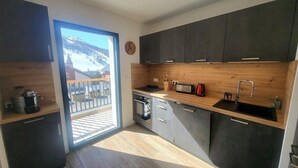 Una cocina moderna con armarios oscuros, una encimera de madera, un microondas, un hervidor y un lavabo.