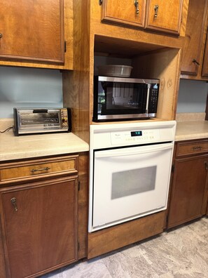 A kitchen with wooden cabinets, a microwave, a toaster, and a dishwasher.