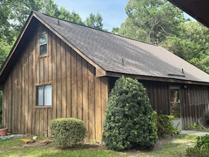 A wooden barn-style building with a sloped roof, a small window, and a door. - DADS PLACE ON TOLEDO BEND LAKE (Many)