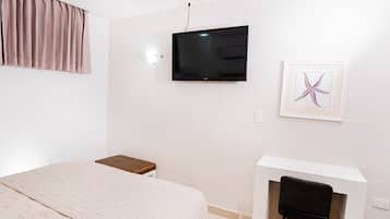 Una camera da letto con un letto, una scrivania con una sedia, una televisione e un quadro appeso al muro.