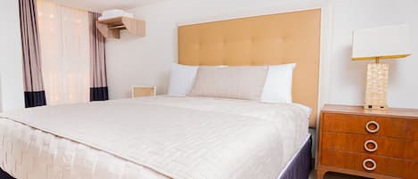 Ruime hotelkamer met een groot bed, een houten nachtkastje en een bedlampje.