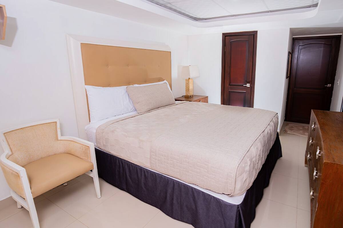 Une chambre bien rangée, avec un lit, une chaise, une commode et une porte.