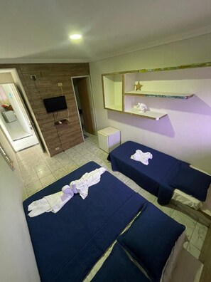 Une chambre d’hôtel avec deux lits, une télévision, un petit bureau et un miroir.