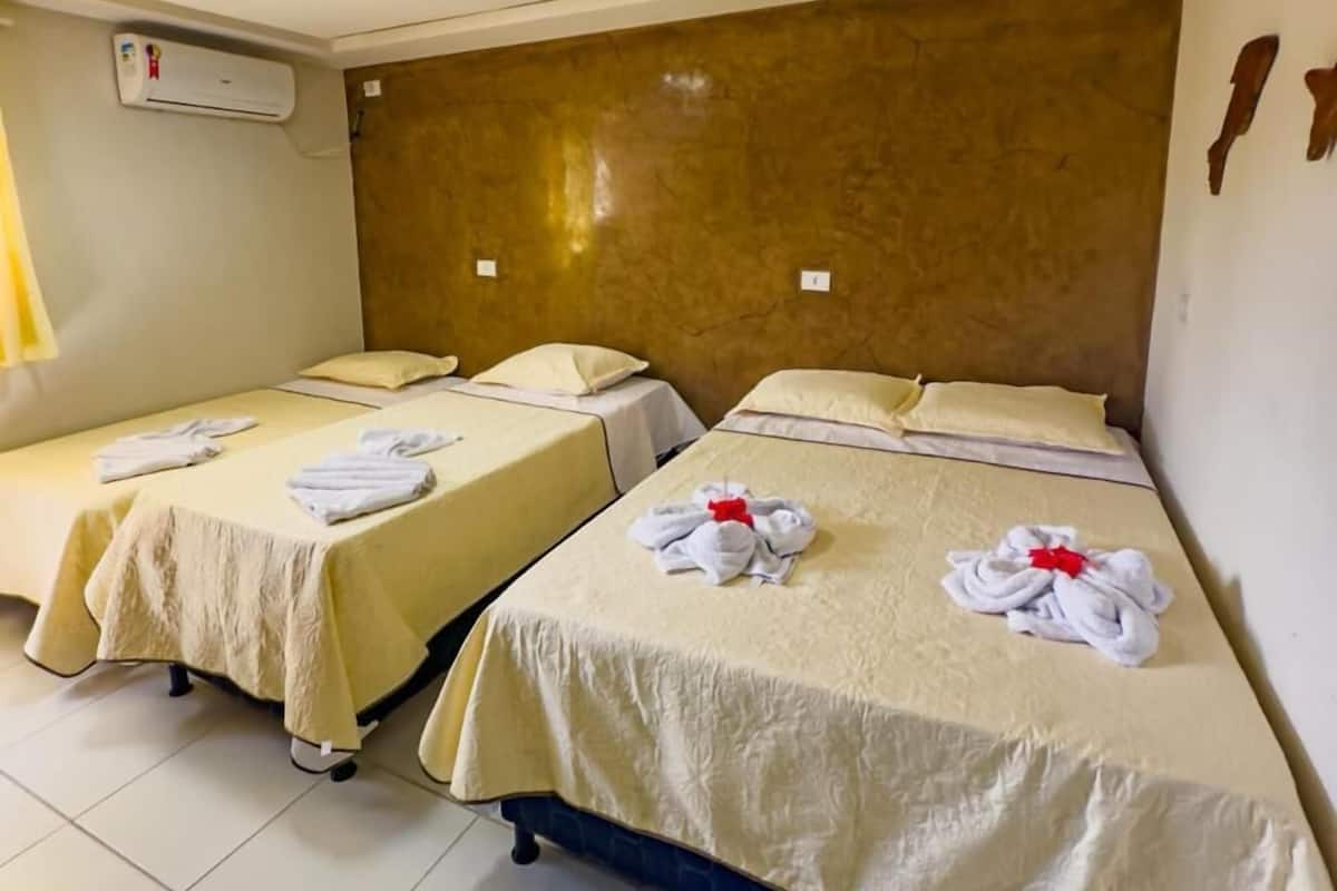Een hotelkamer met twee bedden, elk voorzien van een netjes gevouwen handdoek en een kussen.