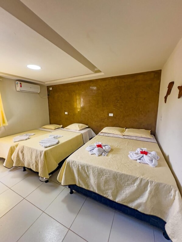A hotel room with two beds, each with a neatly folded towel and a pillow.