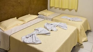 Une chambre d’hôtel avec deux lits, un ventilateur de plafond, un appareil de climatisation et un rideau jaune.