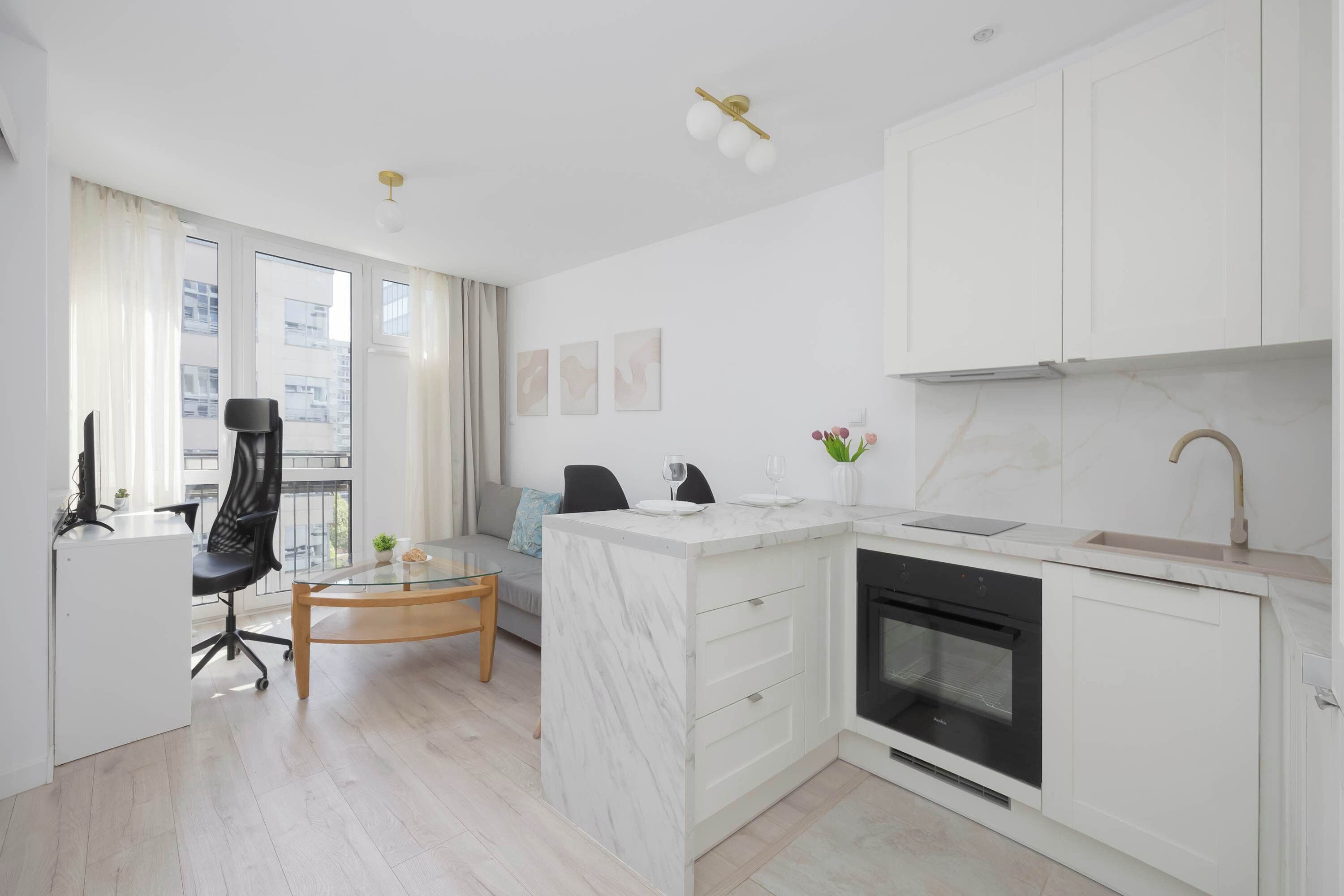 Een moderne keuken met witte kasten, een marmeren eiland en een ingebouwde oven.