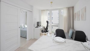 A modern hotel room with a dining area, a balcony with curtains, and a bed with a view.