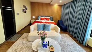 Habitación de hotel moderna con cama, sofá, mesa de centro y vista a la ciudad.