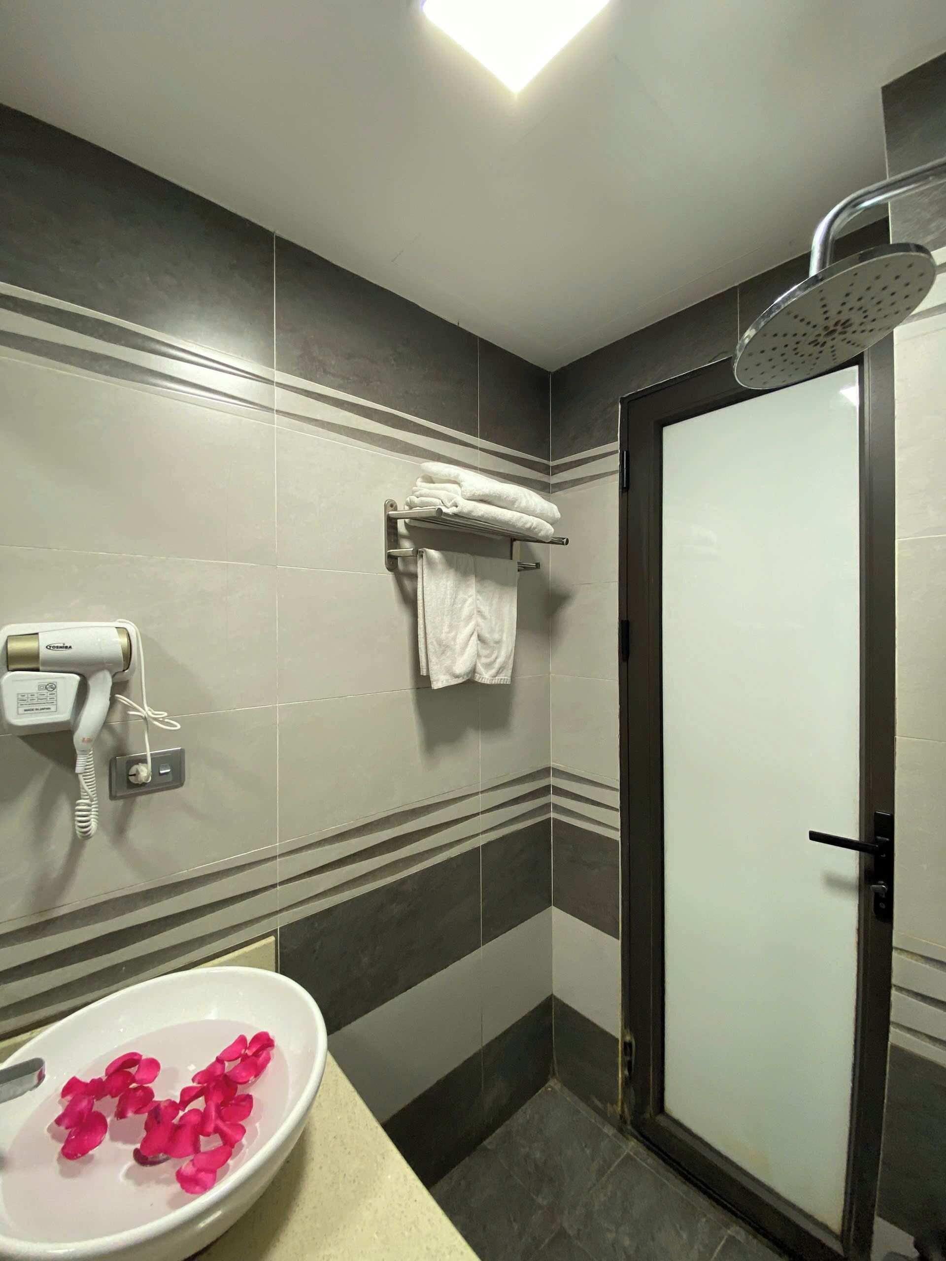 Une salle de bain équipée d’un lavabo, d’un sèche-cheveux, d’un porte-serviettes et d’une douche.