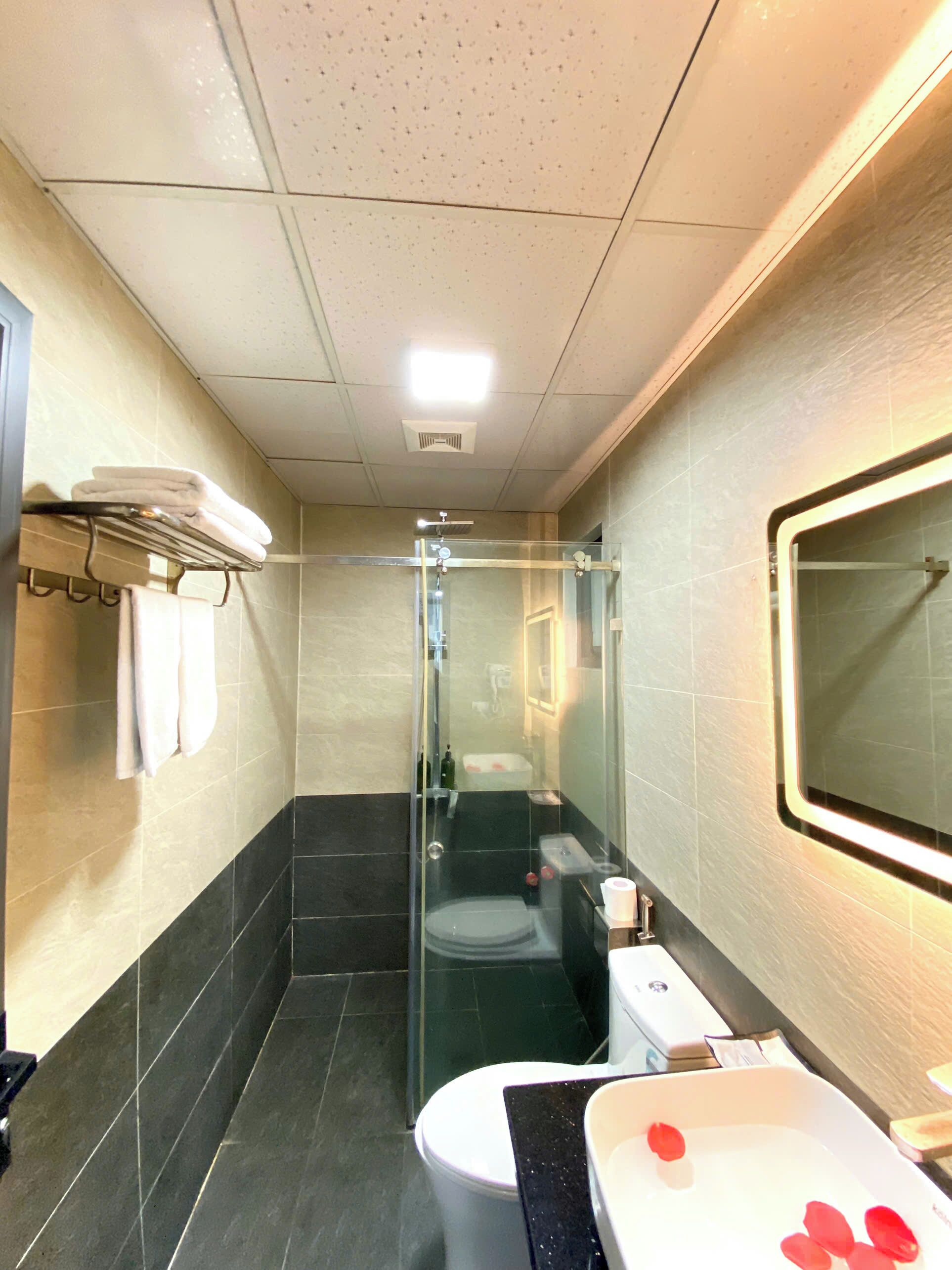 Un bagno con cabina doccia in vetro, un water e un lavandino con specchio.