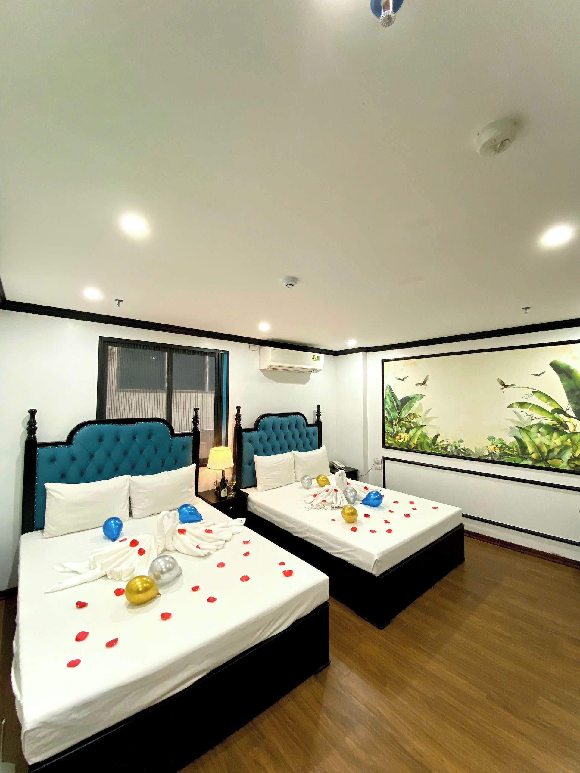 A hotel room with two beds, a large window, an air conditioning unit, and a painting of birds.