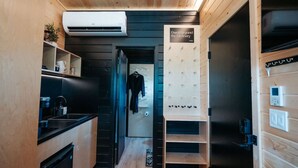 A compact kitchen with a built-in stove, a sink, and a coffee machine. There is a wooden wall with a sign that reads "Dwells Beyond the Ordinary." - Luxurious, Riverside Chalet! Romantic Mountain Views (Johnson Village)