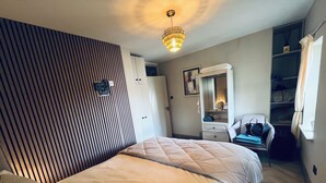 A bedroom with a bed, a wardrobe, a chair, and a mirror. - Cosy apartment in heart of Cork City (Cork)