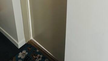 A corner of a room with a door, a light switch, and a wall-mounted wreath.