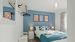 A bedroom with a bed, bedside tables, a hanging light fixture, and wall art.