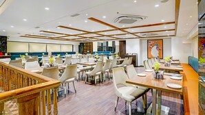 A modern restaurant with wooden panel ceilings, white walls, and a mix of seating options including tables and booths.