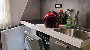 Une cuisine moderne avec des meubles gris, un évier en acier inoxydable et un lave-vaisselle.