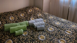 Un lit bien fait, avec une literie à motifs, une tête de lit dotée de compartiments de rangement et une fenêtre avec des rideaux.
