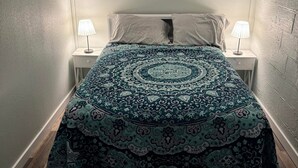 A bedroom with a patterned bedspread, two bedside lamps, and three framed pictures on the wall. - R&R Retreat w/Lake Access. Grand Lake Grove, OK (Wyandotte)