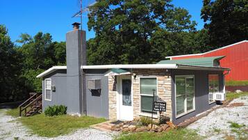 A small, single-story building with a chimney, a front door, and a signboard.