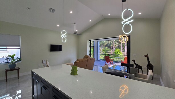 Een moderne keuken met een groot kookeiland, een flatscreen televisie en een eethoek met een bank en stoelen.