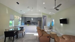 Een ruime woonkamer met een eettafel, banken en een keuken op de achtergrond.