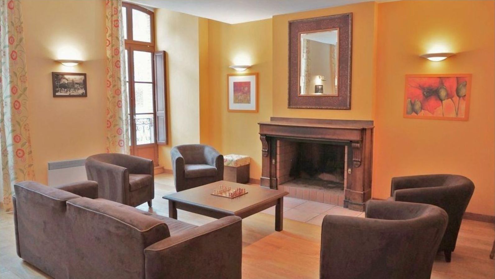 Een gezellige woonkamer met een open haard, comfortabele zitplaatsen en kunstwerken aan de muur.