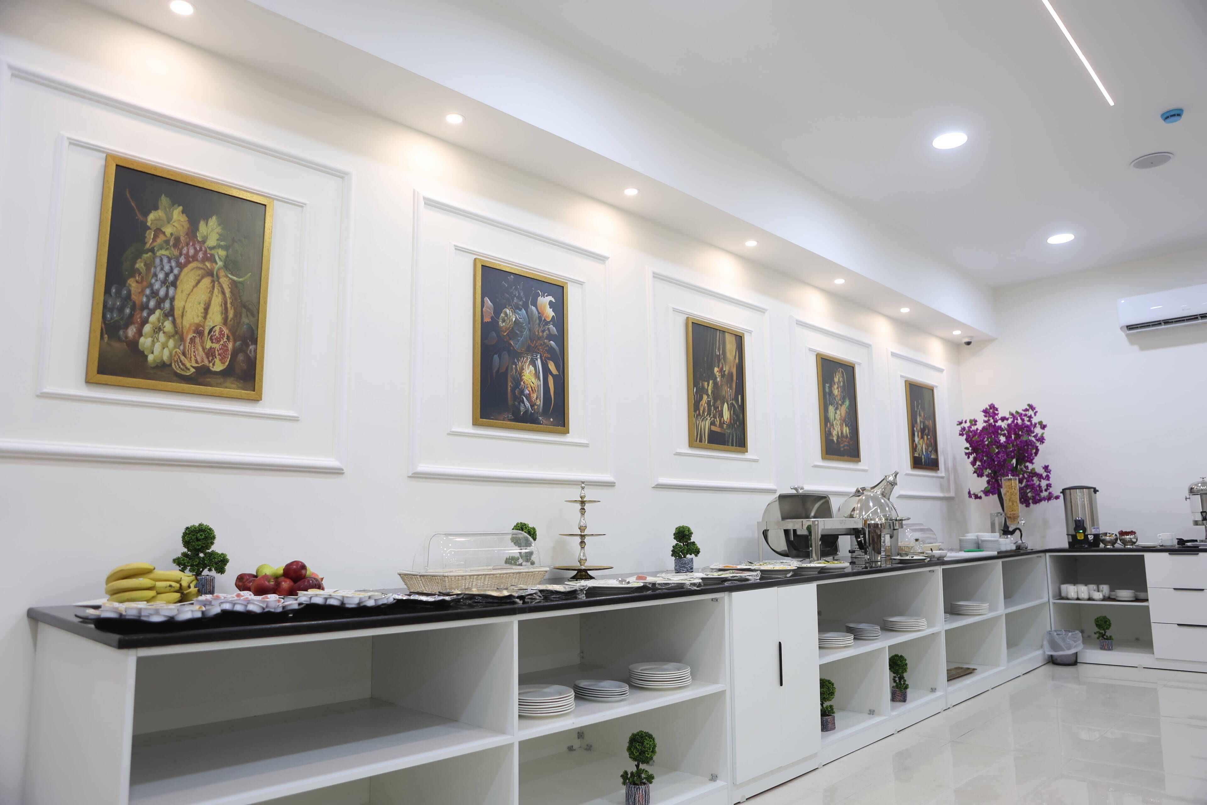Una cocina moderna con armarios blancos, encimera de mármol y obras de arte en las paredes.