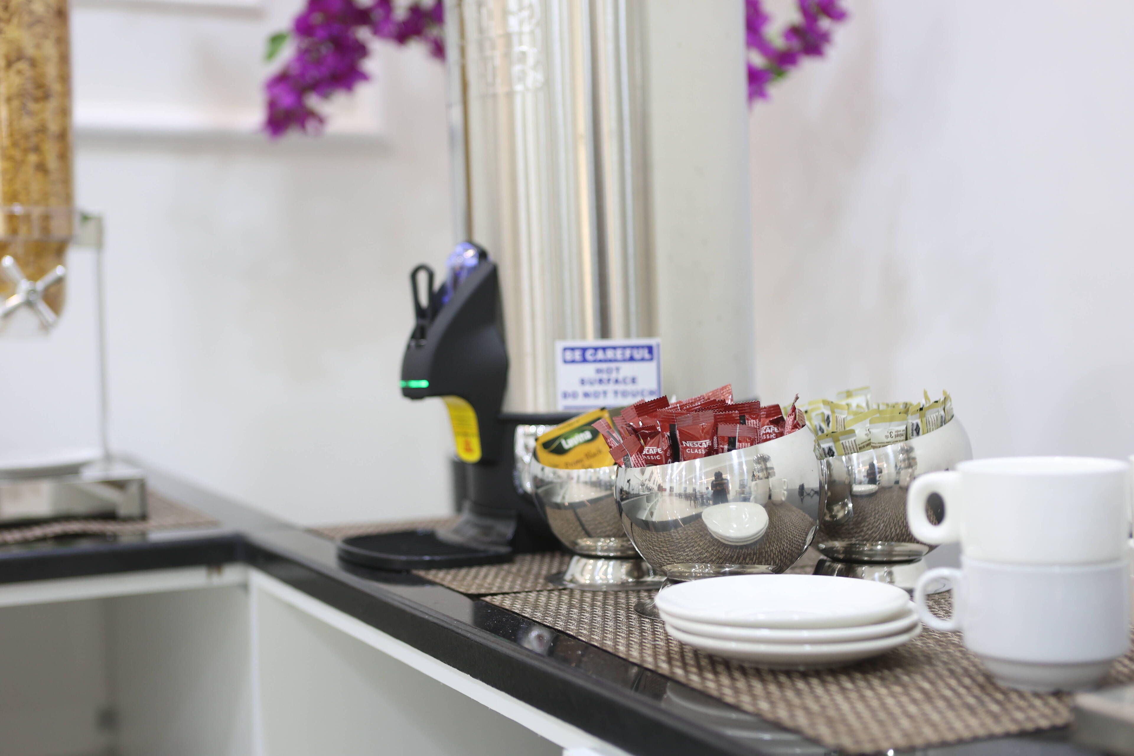 A coffee station with a coffee machine, a bowl of coffee pods, and a cup.