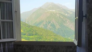 Une chambre avec un lit, une fenêtre et une vue sur les montagnes.