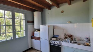 Une cuisine avec une fenêtre, un réfrigérateur, une cuisinière et un four à micro-ondes.