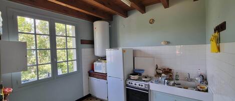 A kitchen with a window, a refrigerator, a stove, and a microwave.