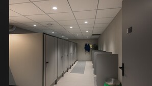 A corridor with cubicles, a trash bin, and a wall-mounted coat rack. - Hystay (Bengaluru)