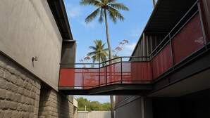 A modern building with a concrete facade, a red balcony, and palm trees in the background. - Hystay (Bengaluru)