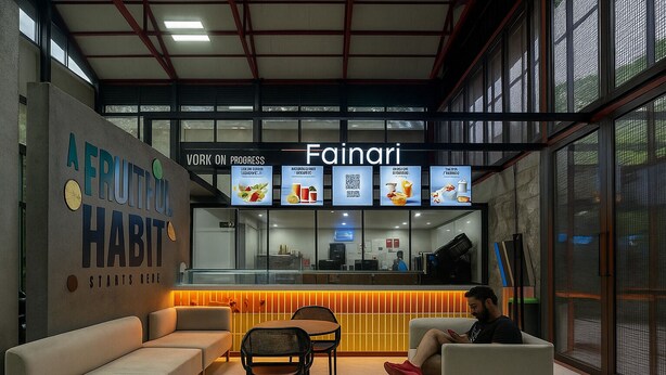 A modern interior with a seating area, a counter with menu boards, and a wall with a health-focused message. - Hystay (Bengaluru)