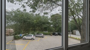 A parking area with cars, trees, and a sign that reads "Courtside Data Kiosk." - Hystay (Bengaluru)