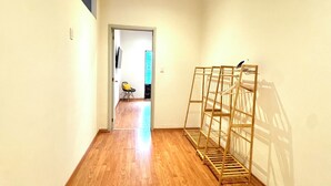 A hallway with wooden flooring, a metal rack, and a door leading to another room.