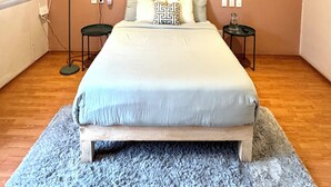 A bedroom with a bed, a ceiling fan, bedside tables, and a floor lamp.